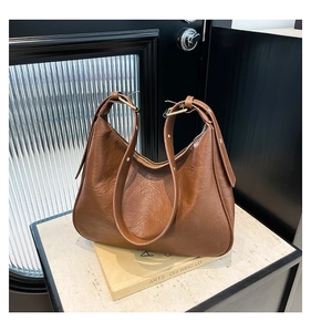 Detail view of brown hobo bag with wrinkled texture, gold buckle and adjustable strap