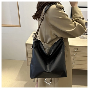 Detail view of black matte leather hobo bag with unique woven strap and padded shoulder