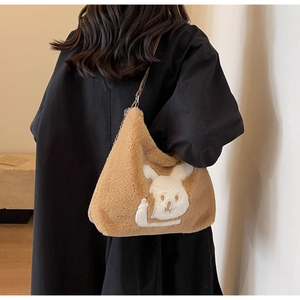 Brown plush tote bag with white rabbit pattern shown on model for size and style