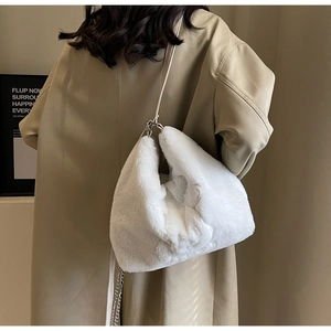 Close-up of fluffy white faux fur shoulder bag with silver chain strap worn by a model