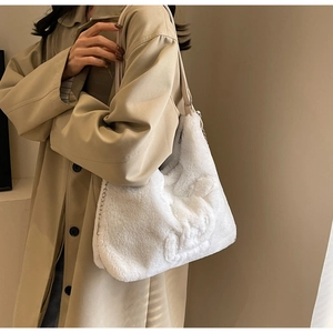 Detail of white plush shoulder bag with embossed texture and metal chain strap
