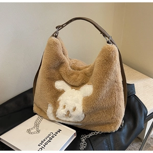 Detail of plush brown hobo bag with cute white rabbit patch and metal chain strap