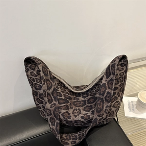 Grande borsa hobo leopardata con ampia tracolla posizionata su una panca nera