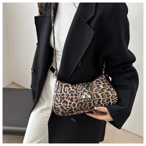 Leopard print baguette shoulder bag with gold butterfly clasp shown on a model