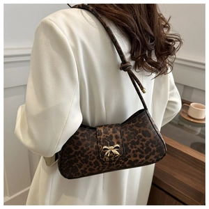 Detail of leopard print underarm bag with gold bow buckle and knotted strap on white blazer