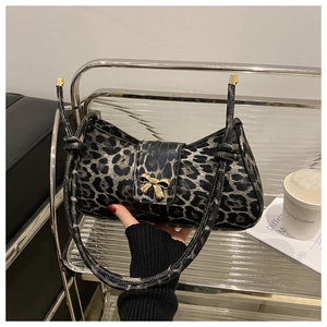 Detailed macro view of leopard print shoulder bag with gold bow clasp and knotted strap