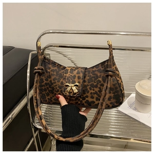 Detail of leopard print underarm bag featuring a gold bow-shaped metal buckle and PU texture