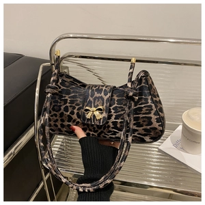 Detail of leopard print underarm bag featuring a golden metallic bow buckle