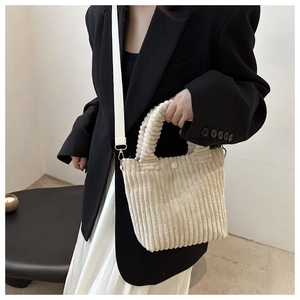 Detail of cream corduroy bucket bag texture with top handle and shoulder strap