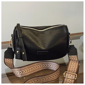 Detail of black PU leather pillow bag with wide ethnic style woven strap and gold zipper