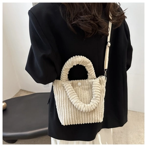 Detail of off-white corduroy bucket bag with pleated handle on model in black suit