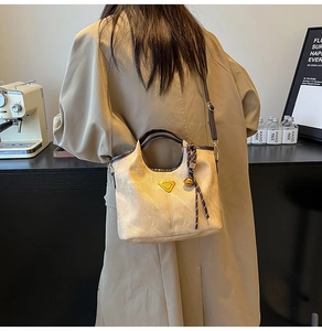 Detail of camel bucket bag with golden logo and dark brown leather handle in a cafe