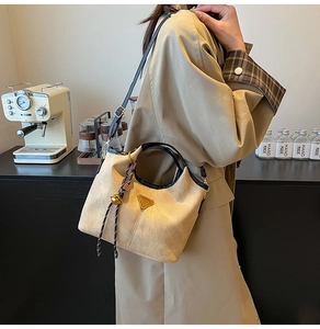 Detail of apricot suede bucket bag with round handles and metal logo on light trench coat