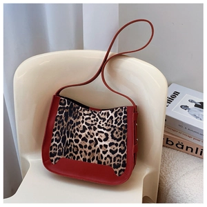Detail of red leather trim and leopard print fabric on a stylish hobo shoulder bag