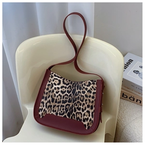Detailed shot of leopard print tote bag with burgundy leather trim on a vintage chair