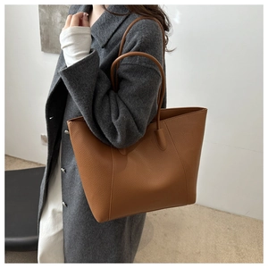 Détail de la texture en cuir marron grainé et des coutures sur un grand sac cabas
