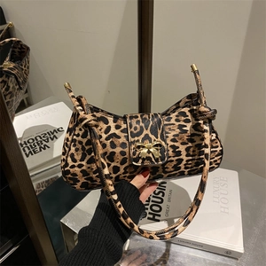 Leopard print underarm bag with gold bow clasp shown in a stylish urban setting