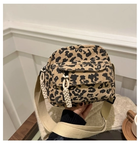 Detail of corduroy leopard print crossbody bag with wide strap and textured rope zipper