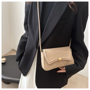 Detail of beige glossy leather crossbody bag with wave-edge flap and gold clasp