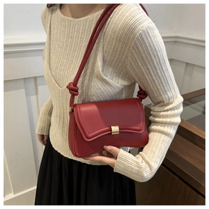 Detail of red leather underarm bag with knot strap and gold magnetic buckle