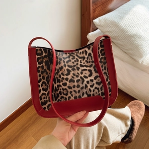 Chic leopard print tote bag with red leather trim shown in a warm lifestyle bedroom setting