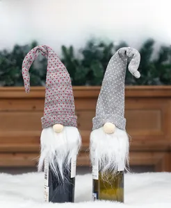 Close-up of knitted Christmas gnome wine bottle covers with long hats and faux fur beards