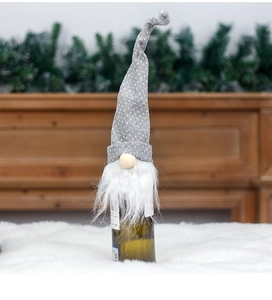 Close-up of a grey knitted gnome bottle topper with white dots and a fuzzy beard