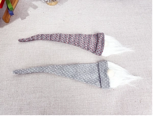 Close-up of two knitted Christmas gnome wine bottle covers with grey and red polka dot hats