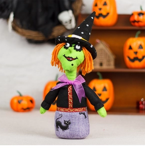 Close-up of plush Halloween witch doll with green face, orange hair and black cat embroidery