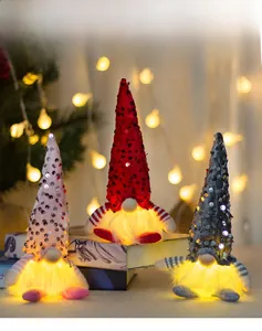 Three glowing Christmas gnomes with sequins and warm lights on books in a cozy setting