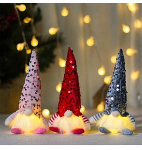 Close-up of three glowing Christmas gnomes with warm LED lights and sequins