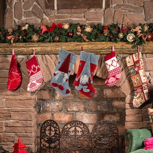 Christmas gnome stockings and knit gift bags hanging on fireplace with festive decor