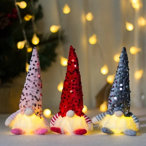 Three sequined Christmas gnomes with warm LED lights in pink, red, and grey tones