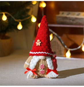 Detail of Christmas gnome plush with red knit hat, gingerbread buttons and white braids