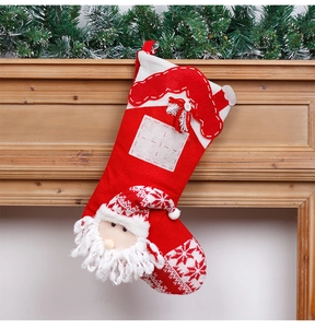 Close-up of a 3D Santa knit Christmas stocking hanging on a rustic wooden fireplace