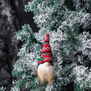 Detail der Weihnachts-Gnom-Dekoration mit Strickmütze an einem verschneiten Tannenzweig