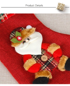 Macro shot of burlap Christmas stocking featuring 3D Santa doll and plaid fabric trim