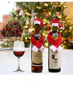 Detail of mini Christmas hat and red scarf decoration set on a wine bottle with festive lights