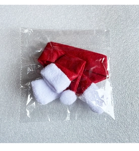 Miniature red Christmas hat and scarf set for wine bottles in protective polybag
