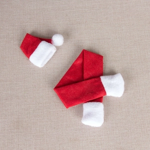 Mini Christmas bottle cover set with red non-woven scarf and hat on woven background