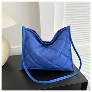 Detail of blue puffer tote bag featuring quilted diamond pattern and smooth nylon texture