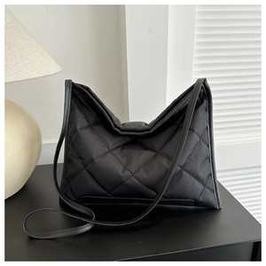 Detail of black quilted puffer shoulder bag with elegant diamond stitch on soft fabric