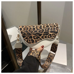 Macro shot of leopard print saddle bag with wide shoulder strap and gold hardware