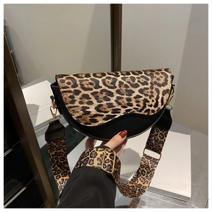 Detail of trendy leopard print saddle bag with wide shoulder strap and gold hardware accents