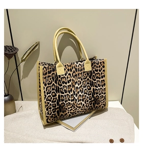 Detailaufnahme einer großen Handtasche mit Leopardenmuster und hellen Griffen auf Mantel