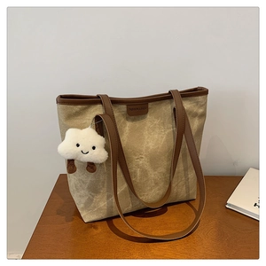 Détail du sac cabas en toile vintage avec anses en cuir et un pendentif peluche mignon