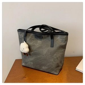 Détail du grand sac cabas en toile grise avec poignées en cuir noir et charm nuage