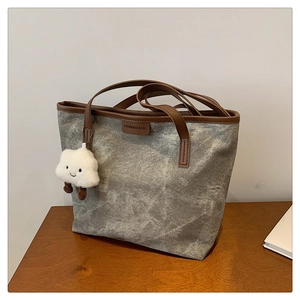 Détail du sac cabas en toile grise avec garniture en cuir brun et pendentif nuage mignon