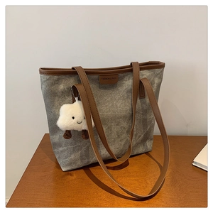 Détail d'un grand sac cabas gris avec anses marron et pendentif nuage en peluche