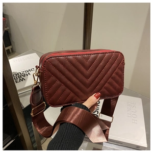 Detail view of wine red quilted leather bag with wide adjustable shoulder strap